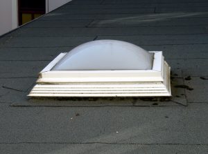 Skylight with a with frame on an asphalt shingle roof with black flashing 
