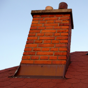 Red brick chimney with metal flashing installed where the chimney protrudes from the roof